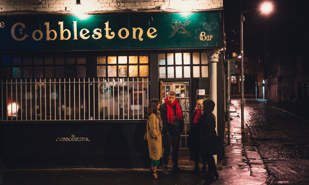 Cobblestone pub with people standing outside 